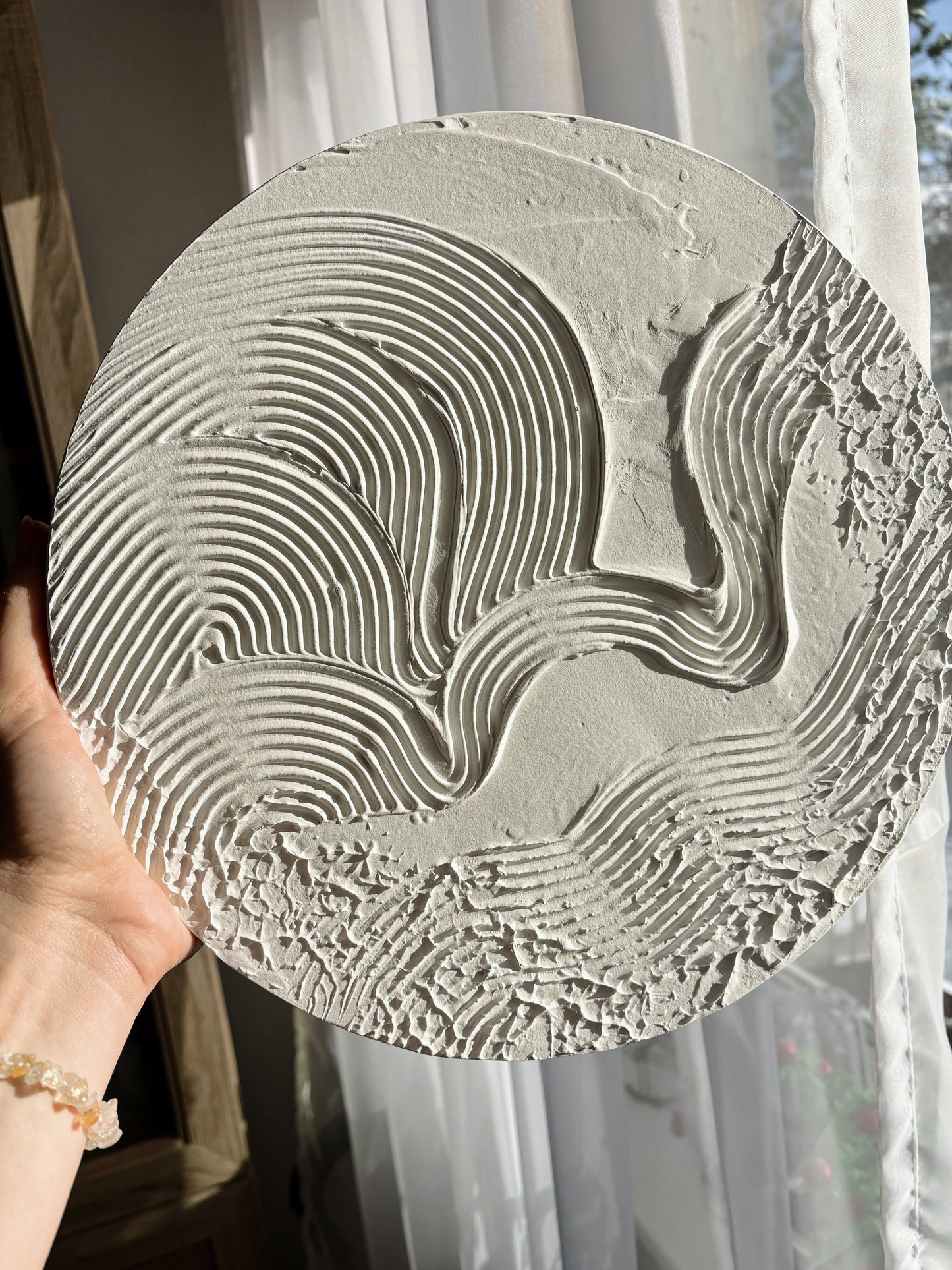 Modern, minimalist, contemporary textured wall art in white, made on round canvas.