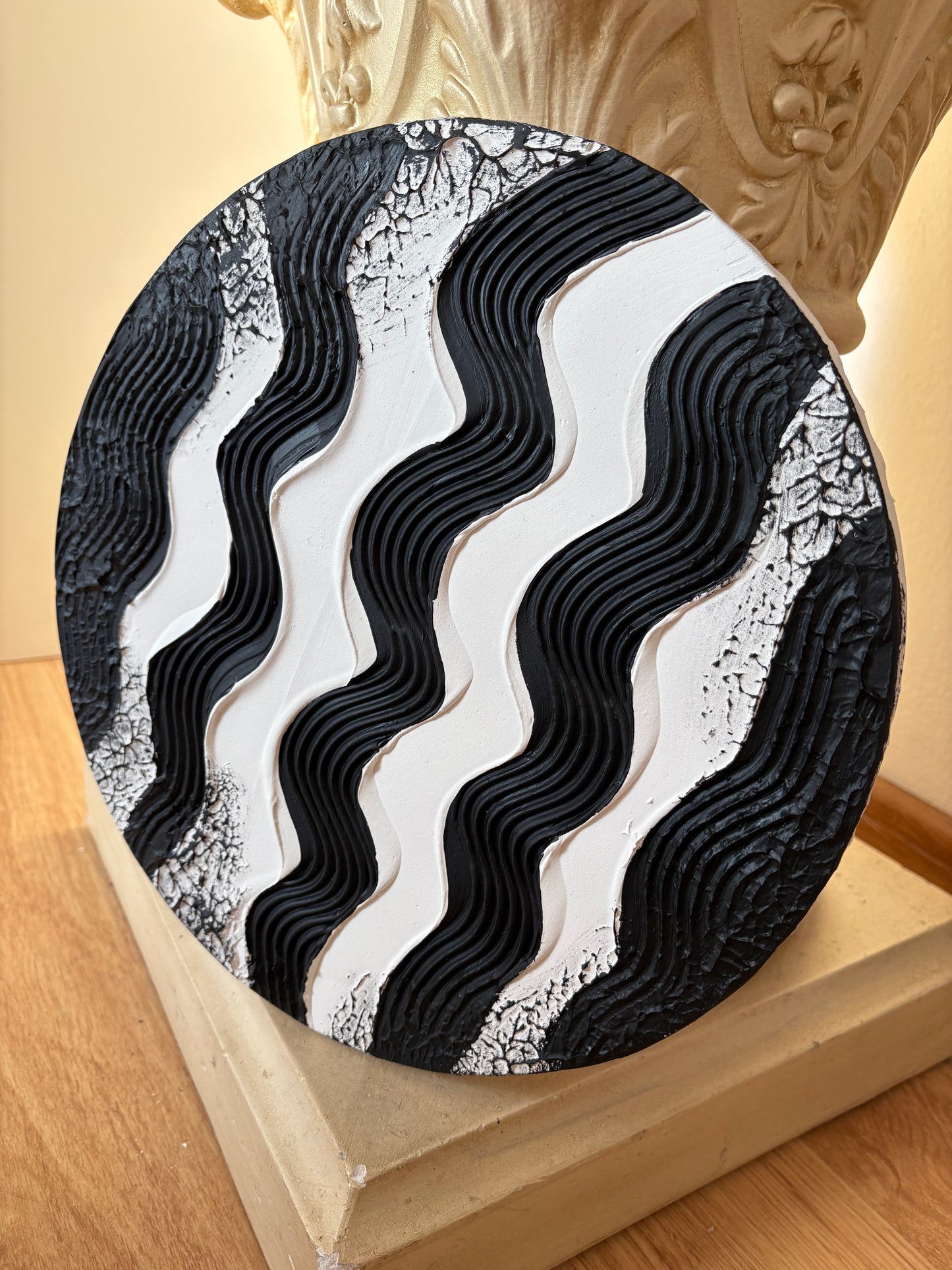 Round black and white textured wall art on a wooden surface