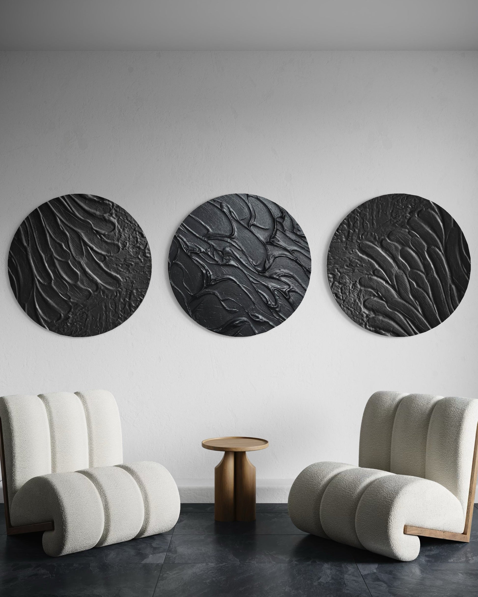 Three circular black wall art pieces in a modern room with two curved white chairs.