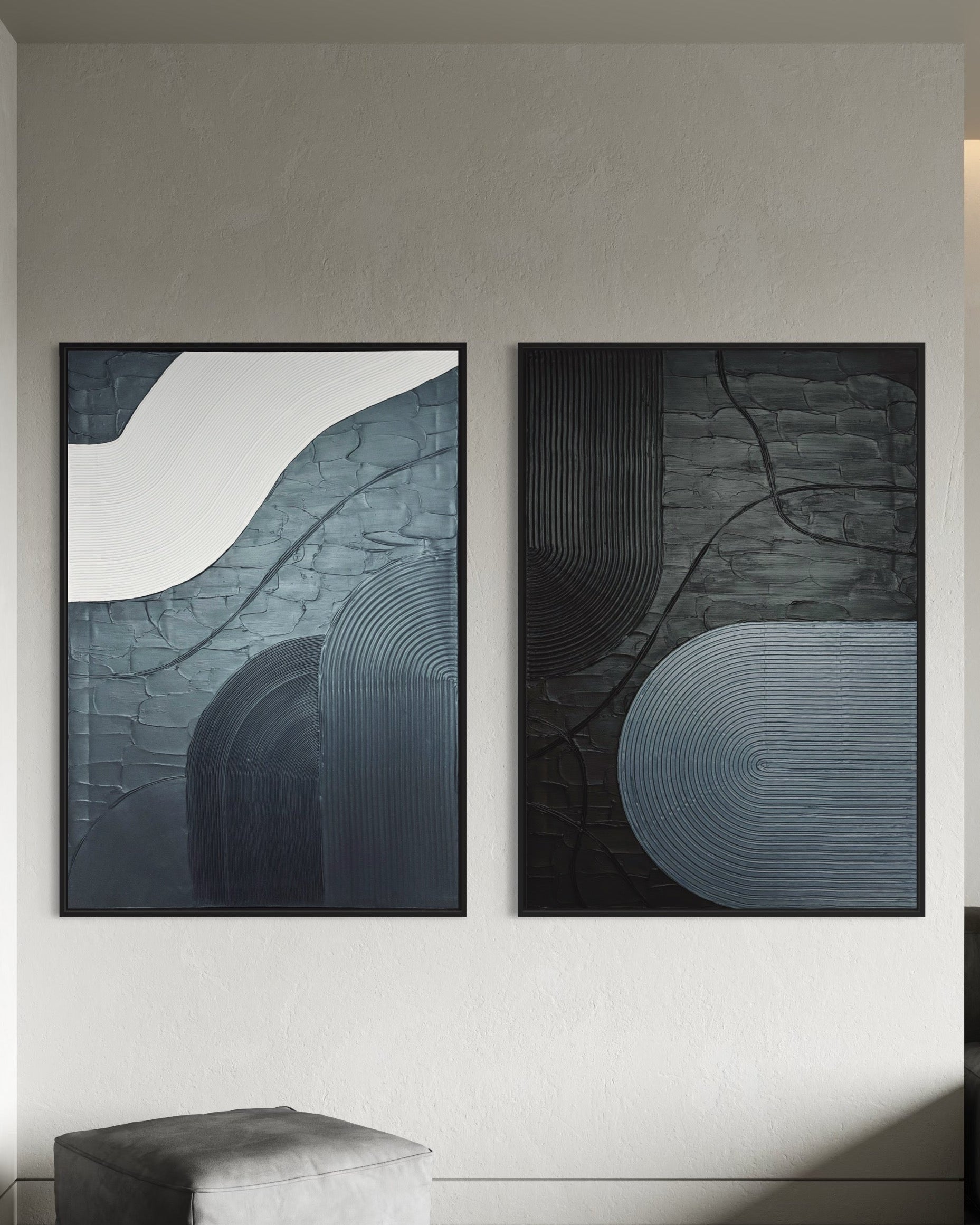 Two abstract paintings in black and grey 3d art minimalist textured wall art on a wall in a modern interior setting.