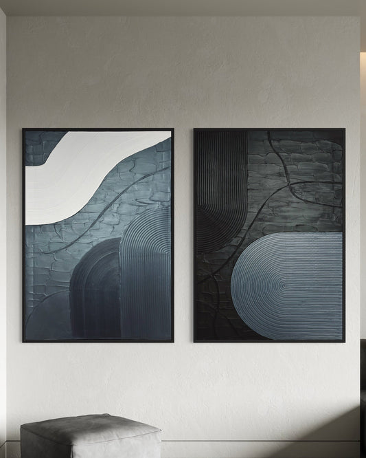Two abstract paintings in black and grey 3d art minimalist textured wall art on a wall in a modern interior setting.