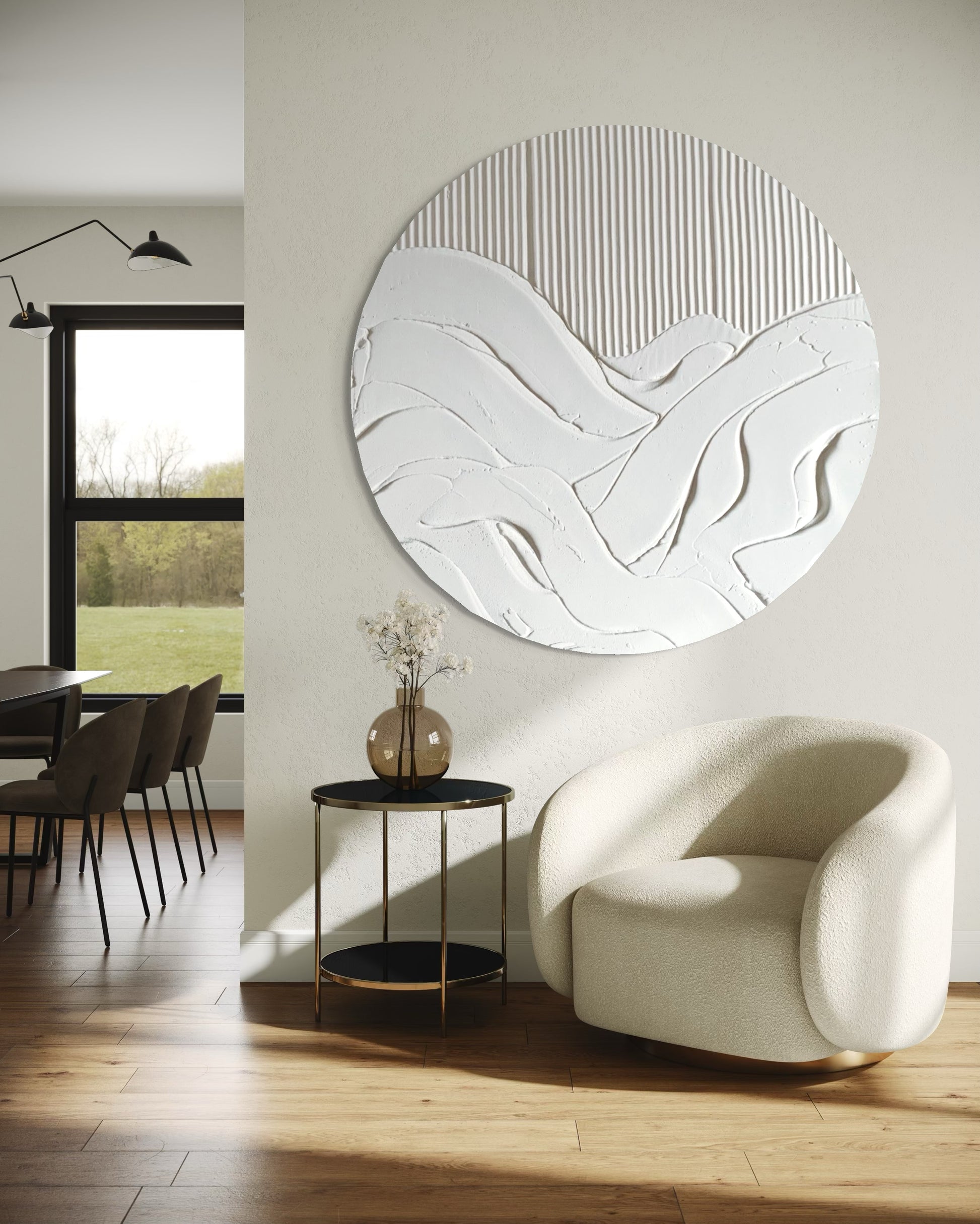 Modern interior with a round abstract wall mirror, white armchair, and dining area.