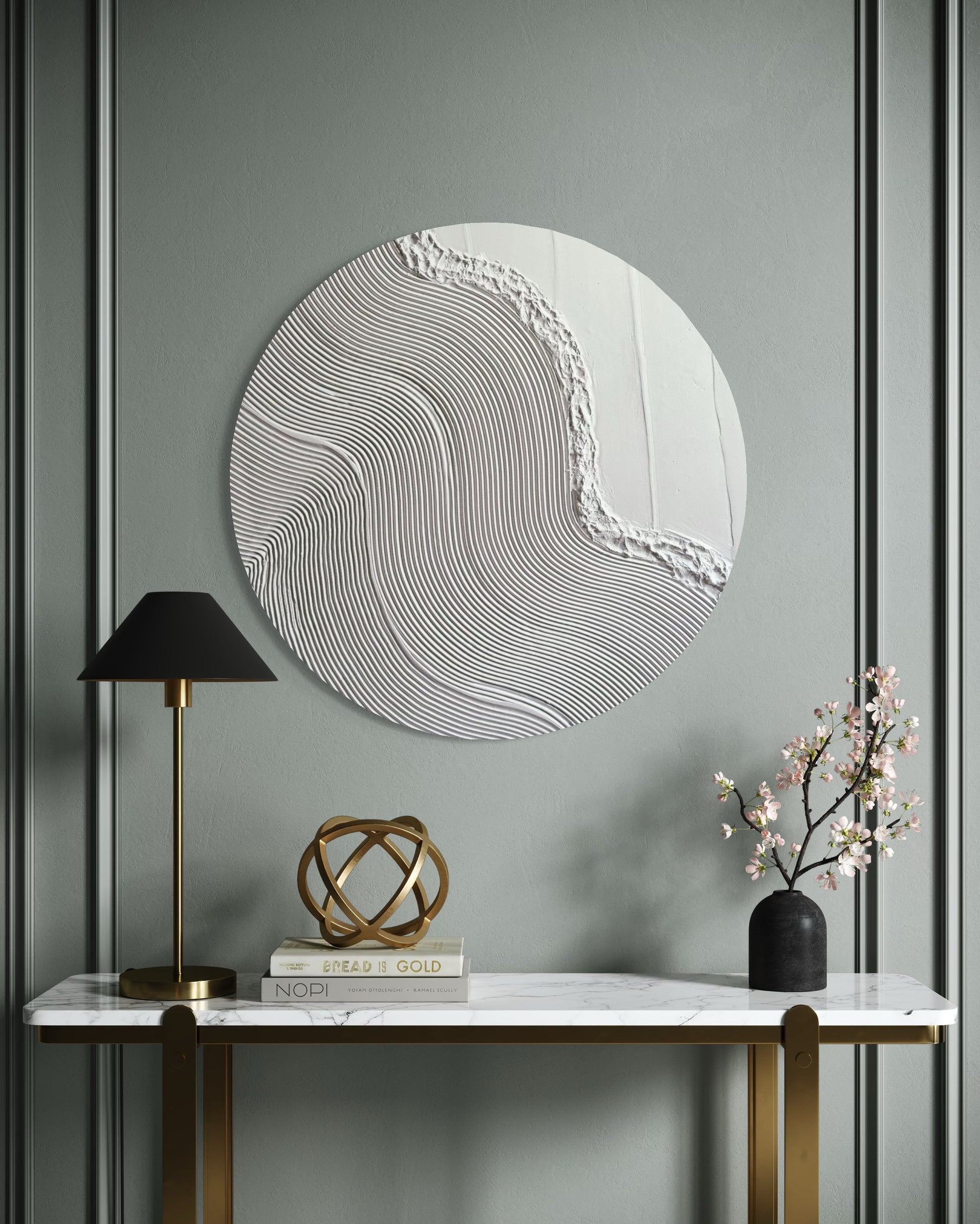 Decorative wall piece on a gray wall with a marble console table and lamp.