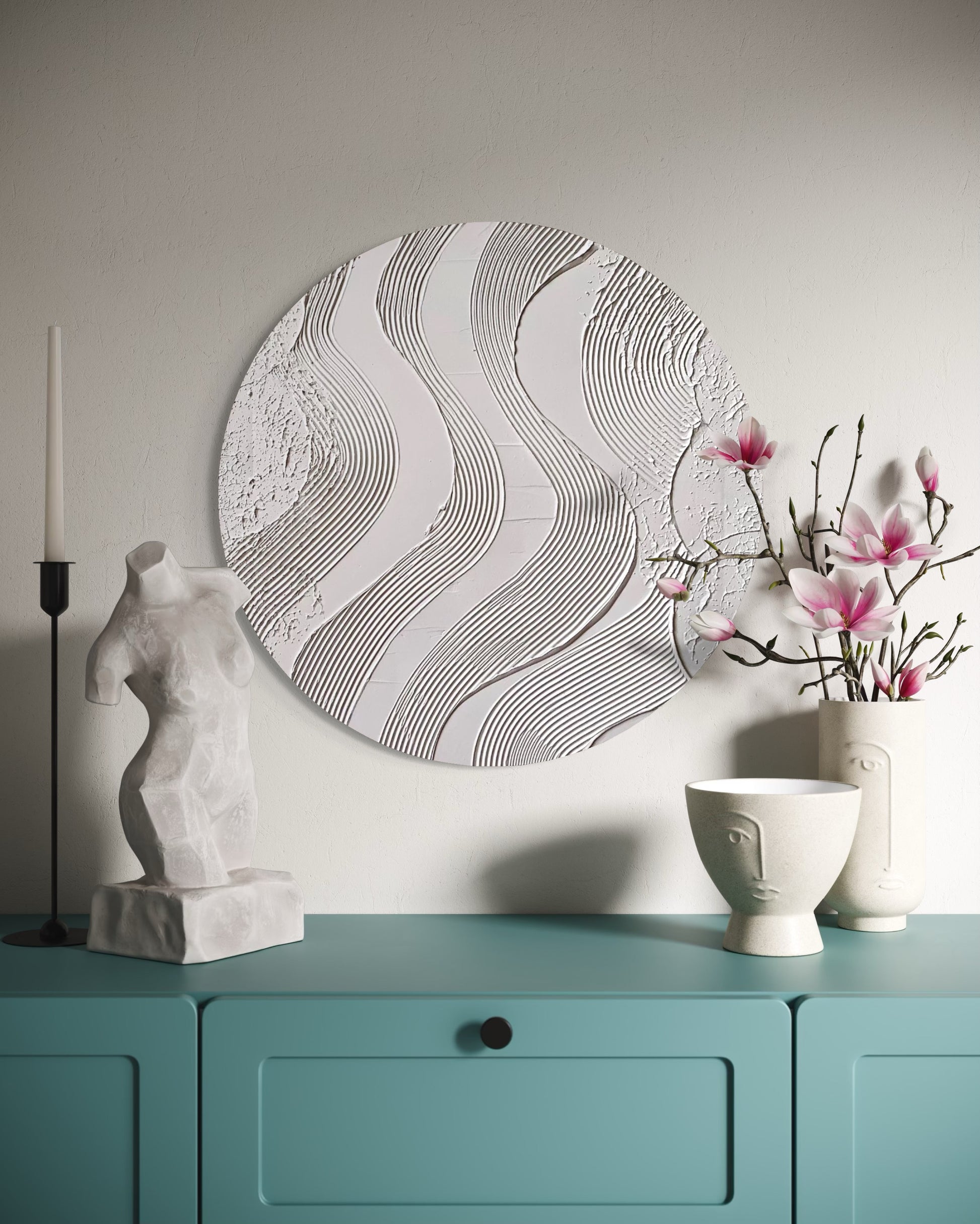 Decorative wall piece, sculpture, and vases on a teal cabinet against a light gray wall.