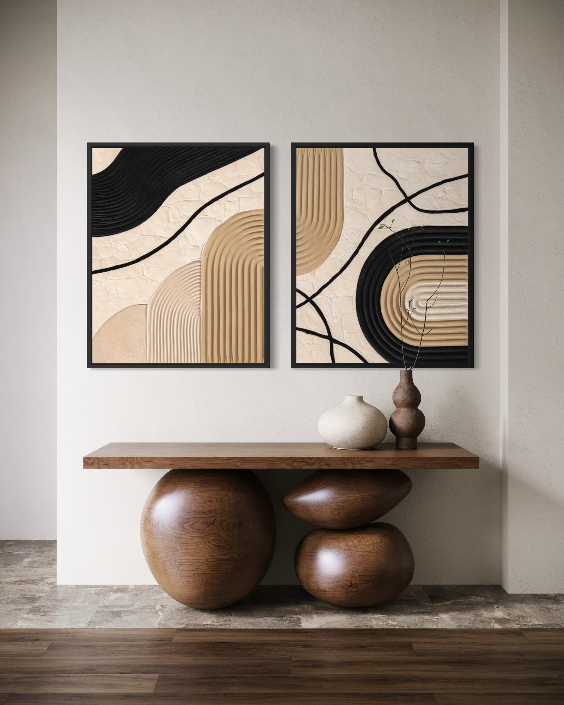 Two abstract wall art pieces above a wooden console table with decorative vases.