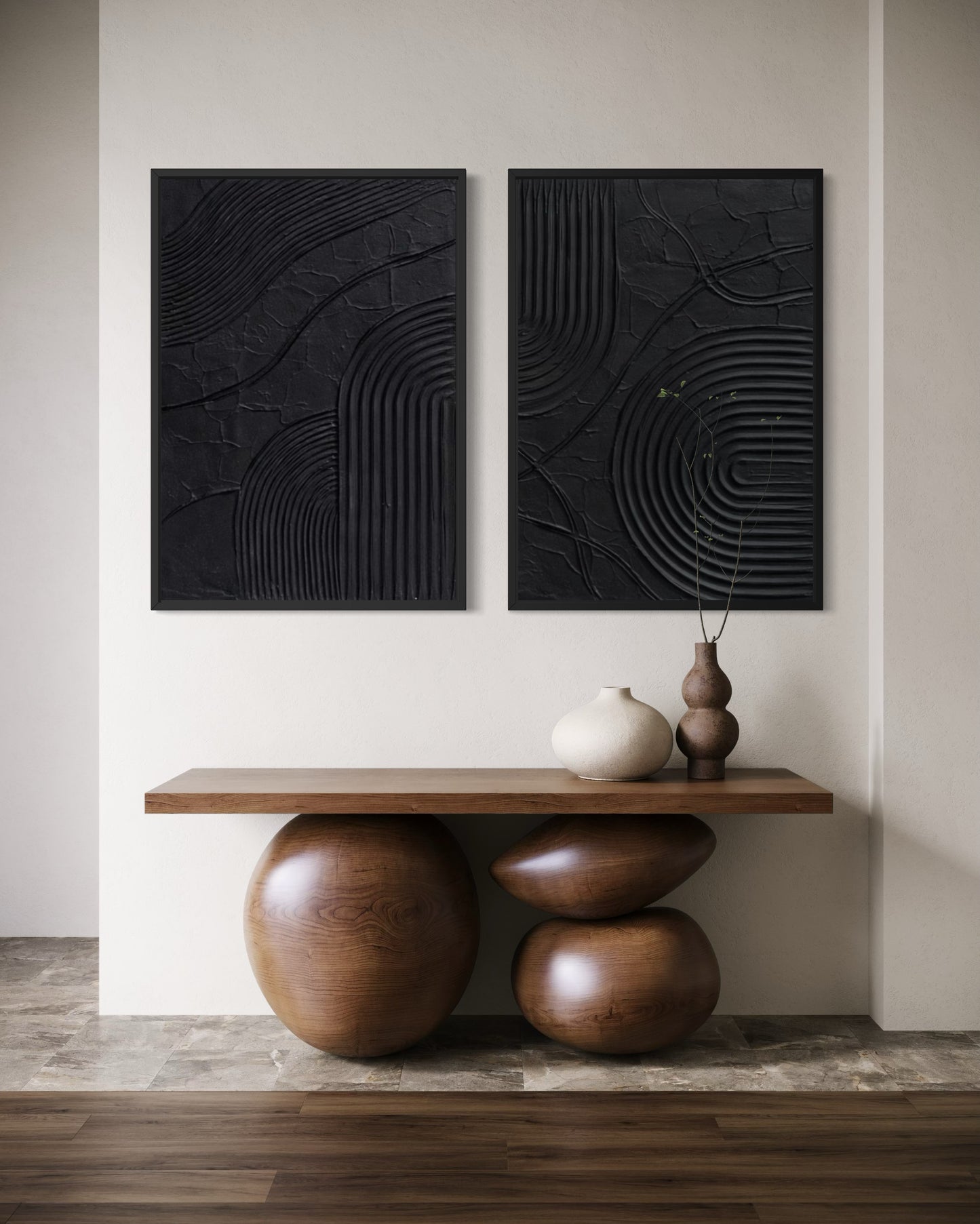 Two black abstract wall arts on a white wall with a wooden console table below.