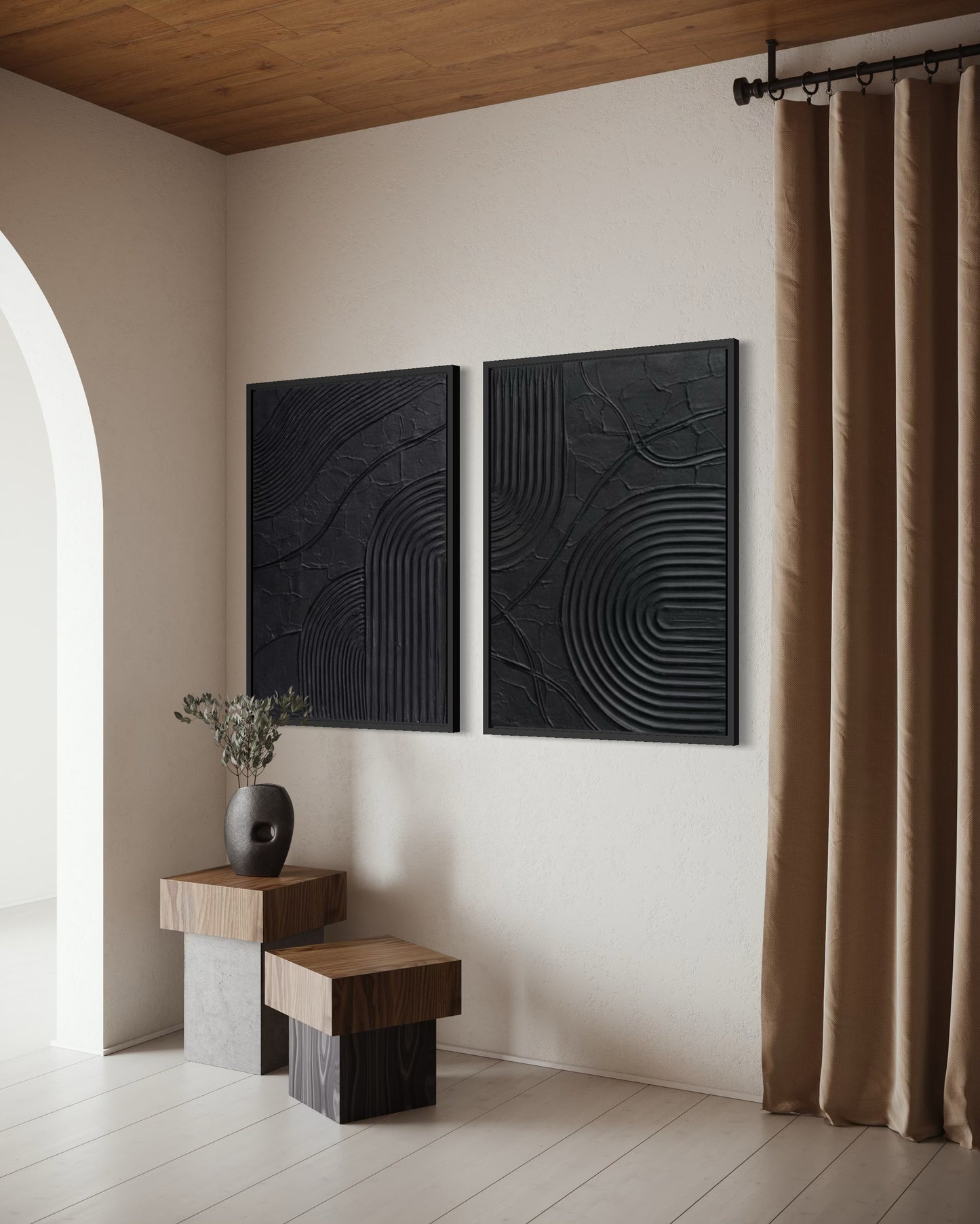 Two black textured wall art pieces on a beige wall with a wooden side table and vase.