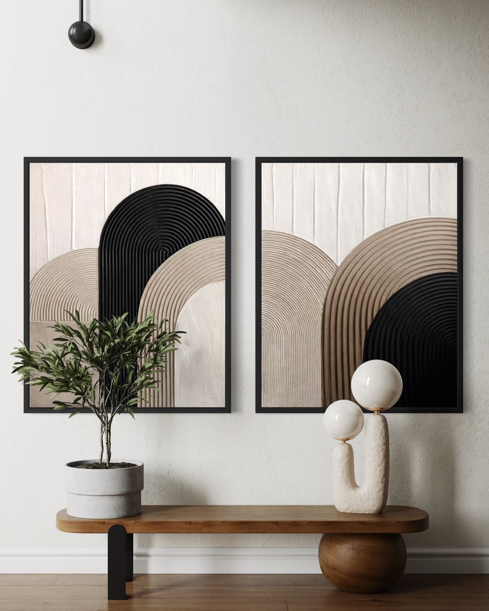 Two abstract art pieces on a wall with a plant and sculpture below.