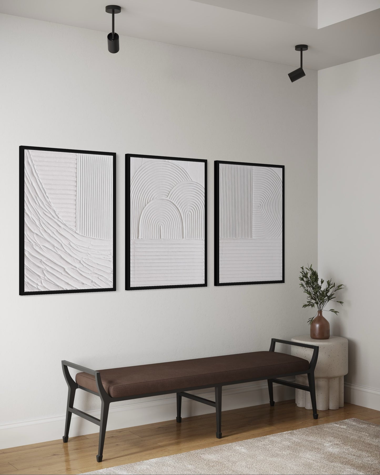 Three black-framed abstract artworks on a white wall above a brown bench.