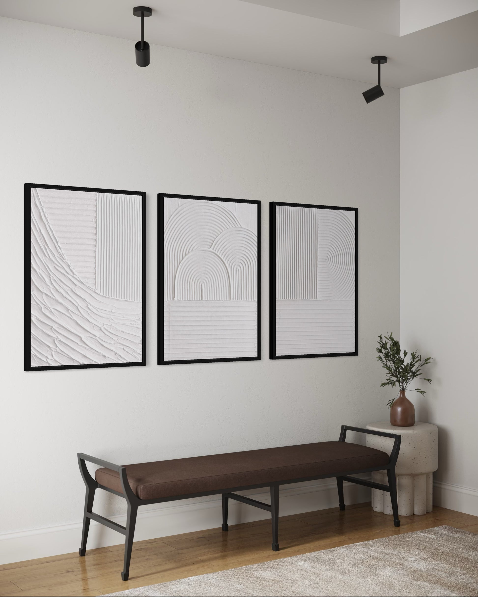Three black-framed abstract artworks on a white wall above a brown bench.