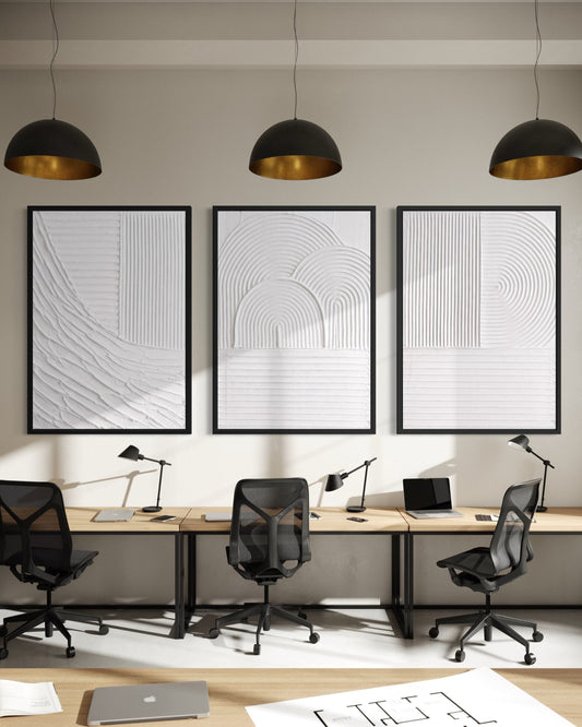 Modern office setup with three framed artworks on the wall, desks, chairs, and office supplies.
