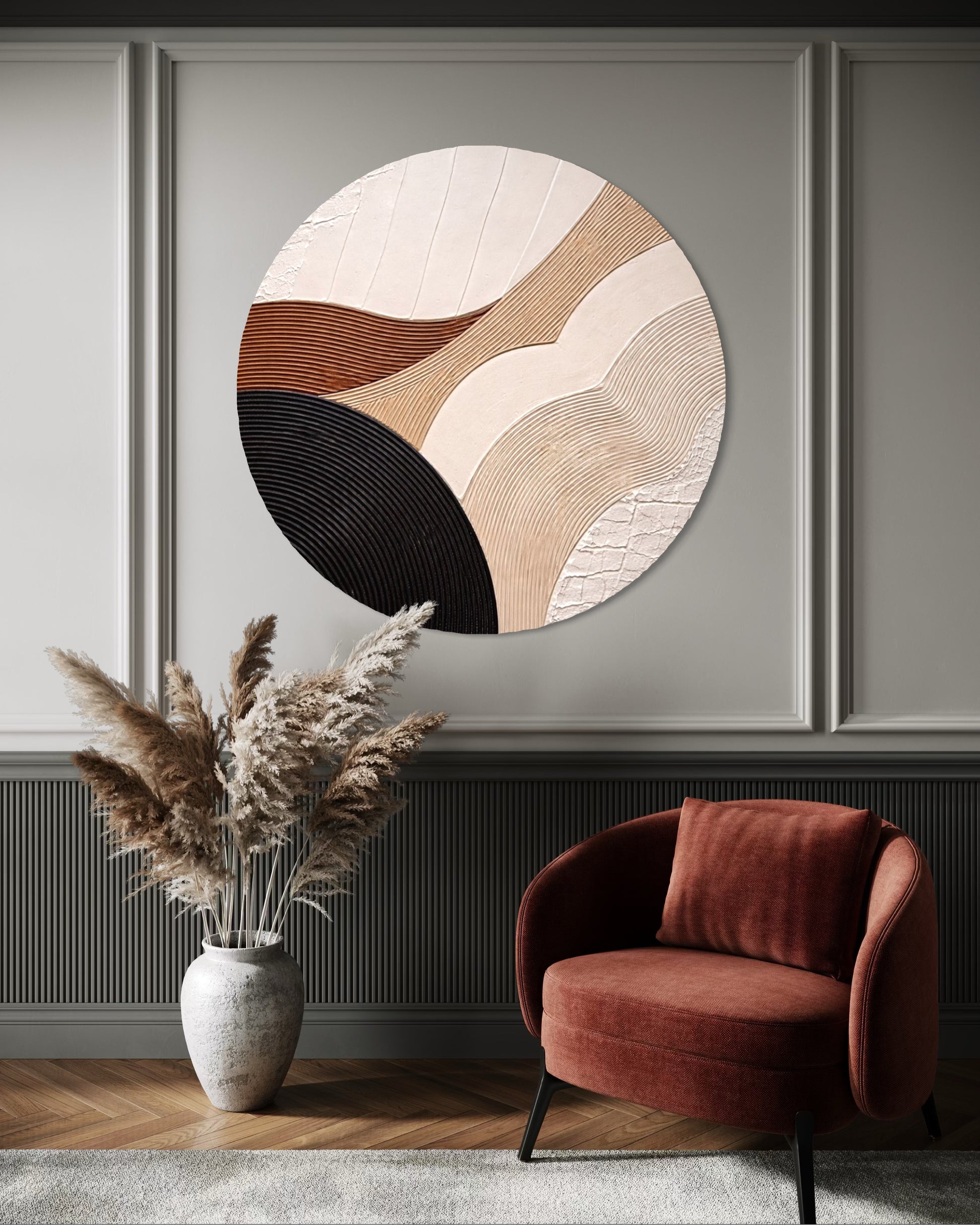 Abstract circular artwork on a wall above a red armchair and vase with dried plants.