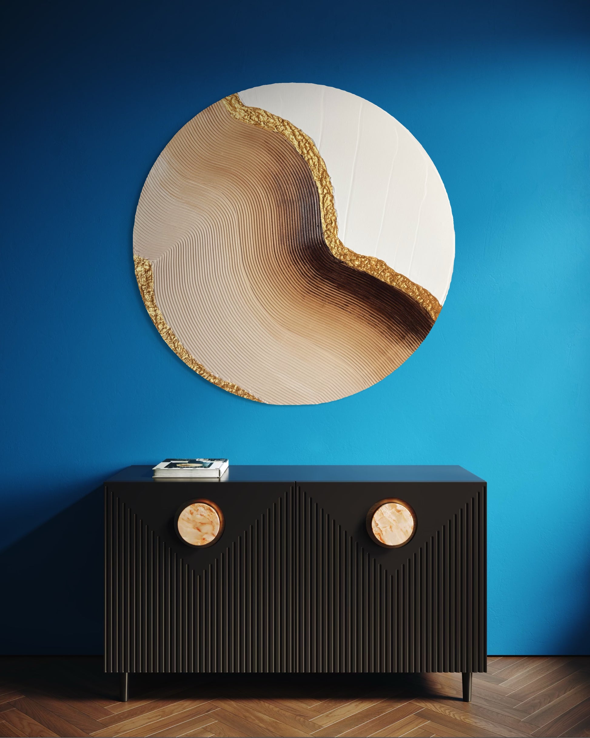 Round wall art piece with wavy design and gold accents on a blue wall above a black console table.
