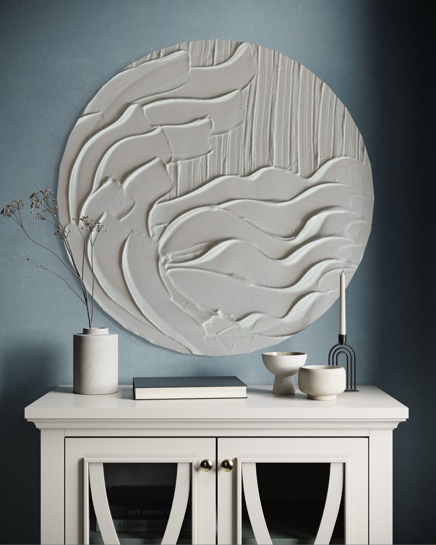 Decorative wall art piece on a gray wall above a white cabinet with decorative items.
