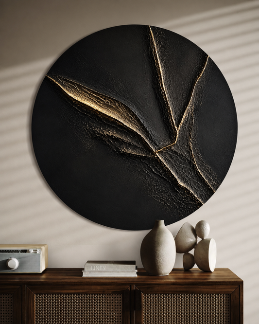 Round black wall art piece with gold accents on a neutral wall above a wooden console table.