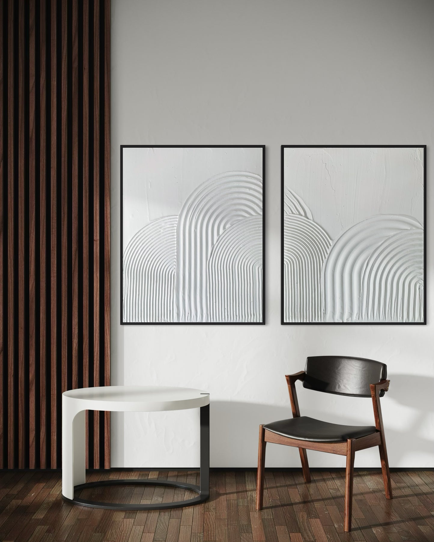 Two abstract wall art pieces textured 3d art in white on a white wall with a modern chair and table.