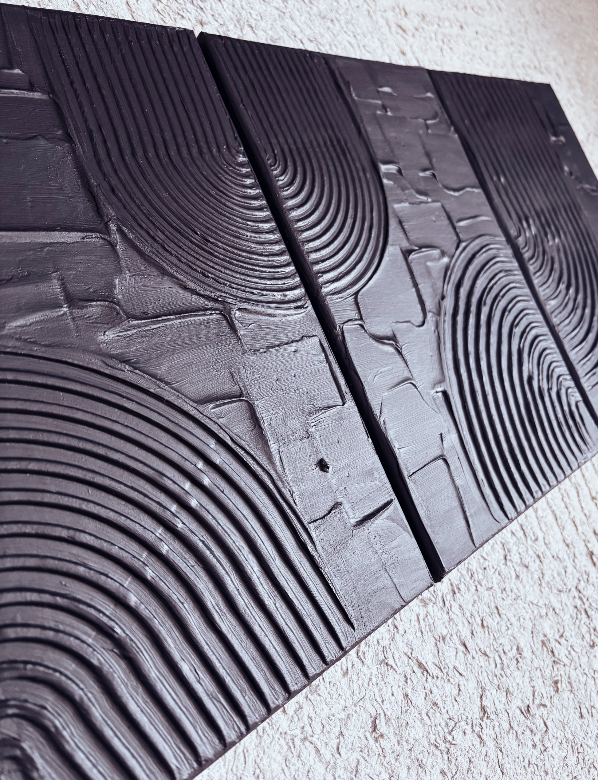 Textured black wall art with geometric patterns